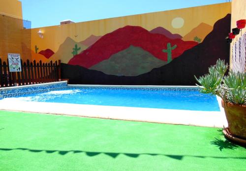 Una piscina con un mural en el costado de un edificio. en Casa Rural Jardín del Desierto, en Tabernas
