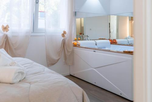 a white bathroom with a mirror and a bed at B&B Infinito in Castelnuovo Rangone