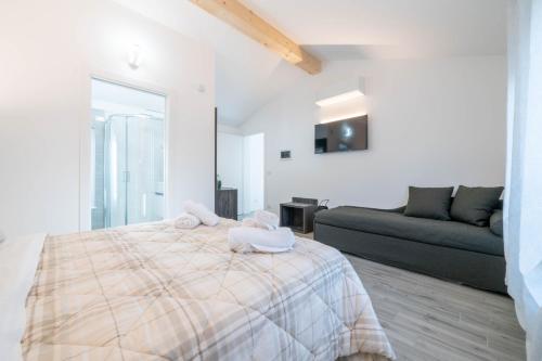 a white bedroom with a bed and a couch at B&B Infinito in Castelnuovo Rangone
