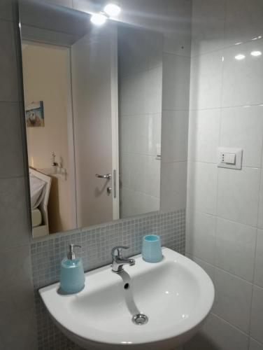 La salle de bains est pourvue d'un lavabo et d'un miroir. dans l'établissement Le Perle, à Torre Ovo