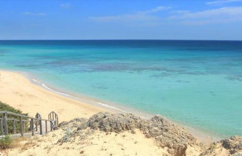a beach with a fence and the ocean at Le Perle in Maruggio