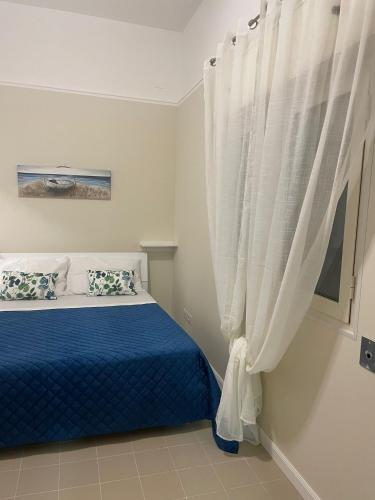 - une chambre avec un lit bleu et une fenêtre avec des rideaux dans l'établissement Le Perle, à Torre Ovo