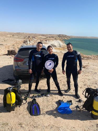 eine Gruppe von drei Personen, die mit einem Frisbee am Strand stehen in der Unterkunft DAKHLA DIVING CAMP in Ad-Dakhla