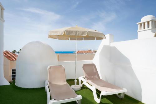 two chairs and an umbrella next to a white building at LABRANDA Bahía Fañabé & Villas in Adeje