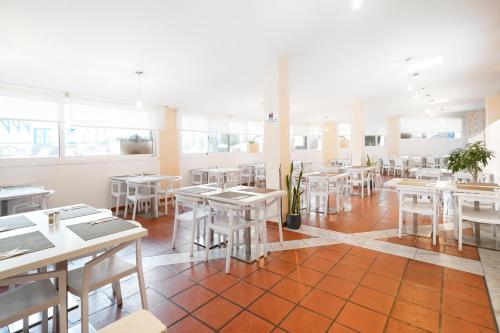 a dining room with tables and white chairs at LABRANDA Bahía Fañabé & Villas in Adeje