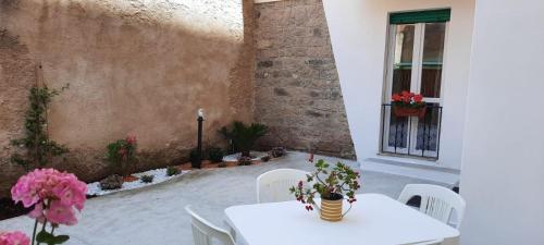 una mesa blanca y sillas con flores en el patio en La Llua Alghero, en Alghero