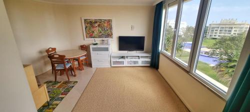 een kamer met een tafel, een televisie en een raam bij T2+1 - Sousa Vila - Apartament with the best pool @ Algarve in Alvor