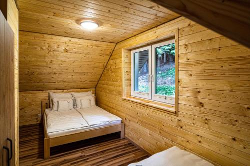 Cama pequeña en habitación de madera con ventana en UROCZYSKO-POLAŃCZYK Prywatne Jacuzzi i Sauna w cenie !!! en Polańczyk