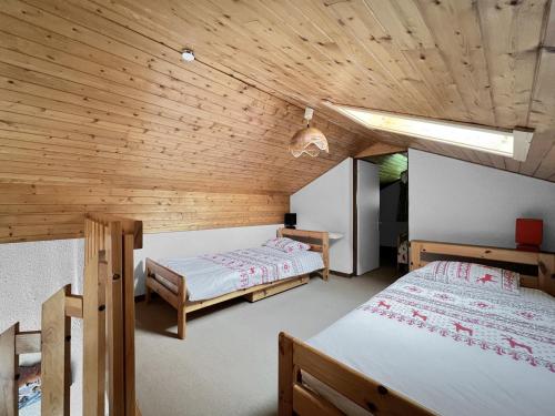 une chambre avec deux lits et un plafond en bois dans l'établissement Duplex 4 Pers PIed de pistes (BA331), aux Carroz d'Arâches