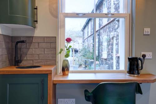 a kitchen counter with a window with a flower in a vase at The Old Laundry eco annex w free parking in Norwich