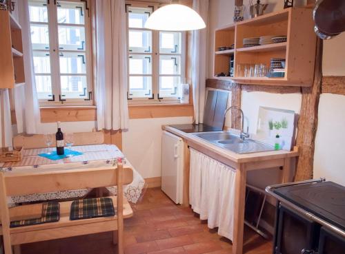 Das Ferienhaus Wernigerode - direkt "Am kleinsten Haus" von Wernigerode في فيرنيغيروده: مطبخ مع حوض وموقد ونوافذ