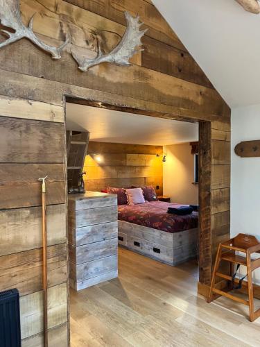 a bedroom with a bed and a wooden wall at Keepers Cabin - Hot tub in Kings Lynn