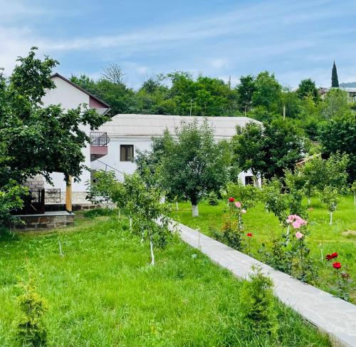a garden with trees and flowers in front of a white building at Spitak Tun in Ijevan