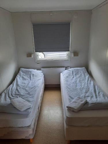 twee bedden in een kleine kamer met een raam bij Vinland Apartment 1 in Egilsstadir