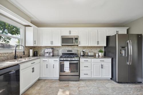 una cocina con armarios blancos y electrodomésticos de acero inoxidable en Charming Contemporary Family Home home, en Glenview