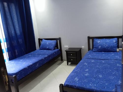 twee bedden in een kamer met blauwe lakens bij Résidence lilia jabal mdiq in M'diq