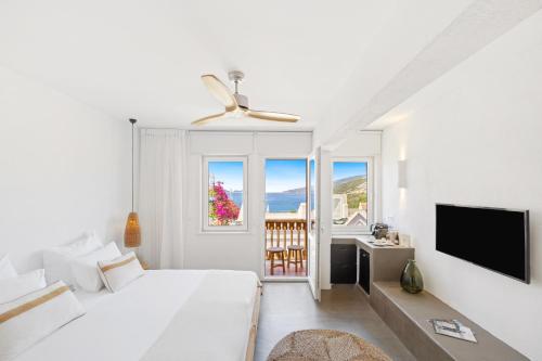 a white bedroom with a bed and a flat screen tv at Kalkan Han Hotel in Kalkan
