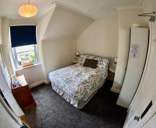 a small bedroom with a bed and a window at Hunters Guest House in Brodick