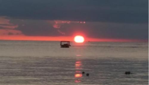 a sunset over the ocean with a boat in the water at Seacret Studios - Cozy Jamaican Retreat apts in Negril