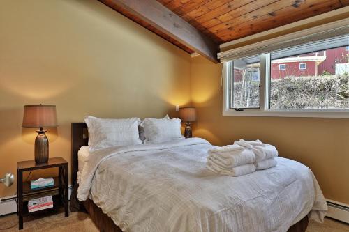 a bedroom with a bed with white sheets and a window at Alpine Court Chalet home in Killington