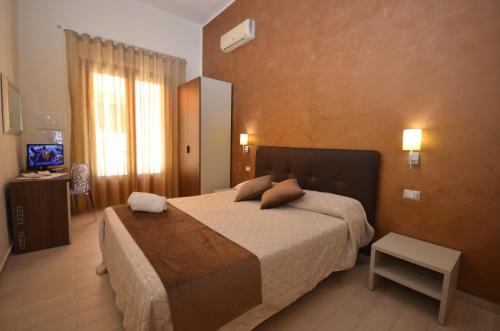 Habitación de hotel con cama y TV en Trigrana Vacanze Hotel, en Castelluzzo