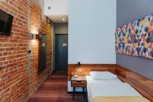 een slaapkamer met een bed en een bakstenen muur bij Hotel Tobaco Łódź in Łódź