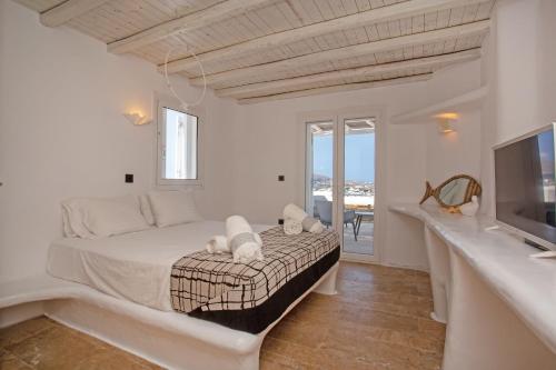 a white bedroom with a bed and a television at Nuera Villa in Mýkonos City