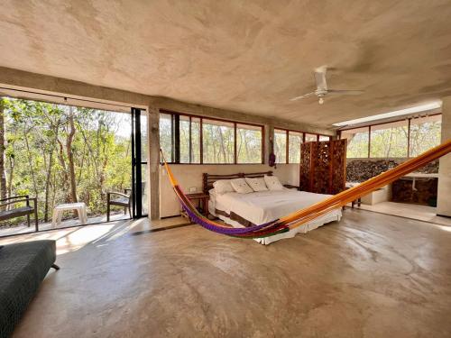 1 dormitorio con hamaca en una habitación con ventanas en El Encanto - Hotel Boutique, en Chichén Itzá