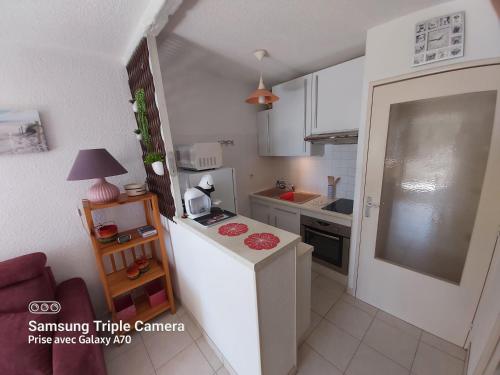 Elle comprend une petite cuisine équipée d'un réfrigérateur blanc et d'un comptoir. dans l'établissement Coquet Studio Centre Port Cap D'Agde, au Cap d'Agde