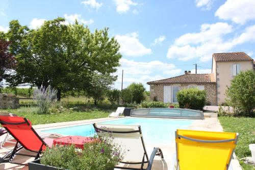 une piscine avec des chaises et une table ainsi qu'une maison dans l'établissement Le Grand Gîte, à Pellegrue