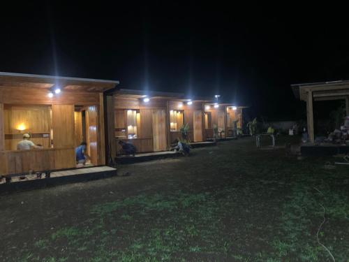 a row of wooden buildings with people sitting outside at night at Buahan Sweet Glamping ( BSG) in Kubupenlokan