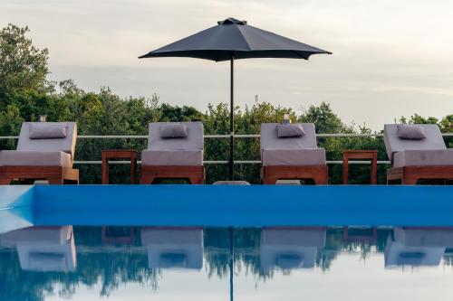 una piscina con sillas, sombrilla y sombrilla en Villa Erato, en Tsoukaladhes