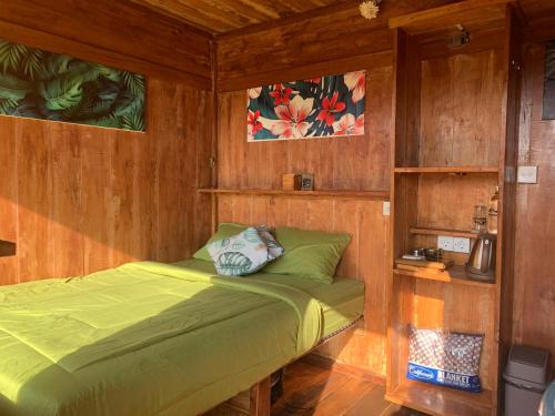 a bedroom with a green bed in a wooden room at Buahan Sweet Glamping ( BSG) in Kubupenlokan