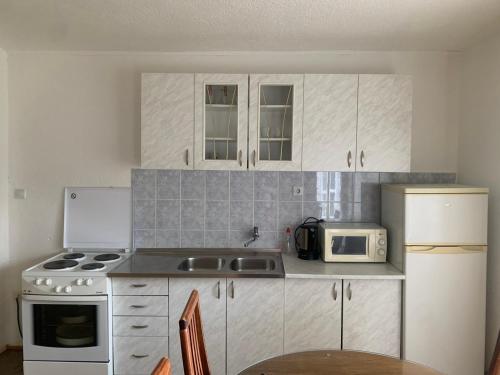 a kitchen with white cabinets and a sink and a microwave at Guest House Šobić in Šipovo