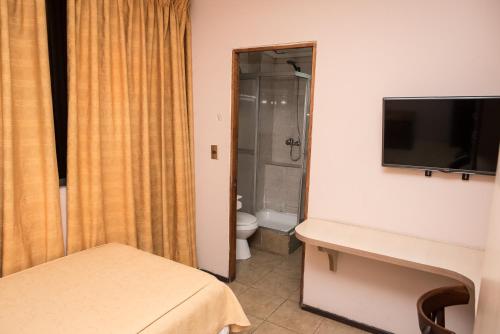 a bathroom with a toilet and a television on a wall at Hotel NIKYASAN in Antofagasta