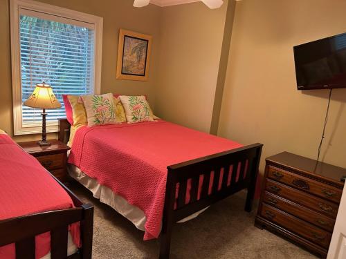 a bedroom with a bed with a redspread and a television at Unique 3BR, 1 of 5 Condos w/Huge Poolside Patio, Steps to Beach & Pier, Gated in Tybee Island