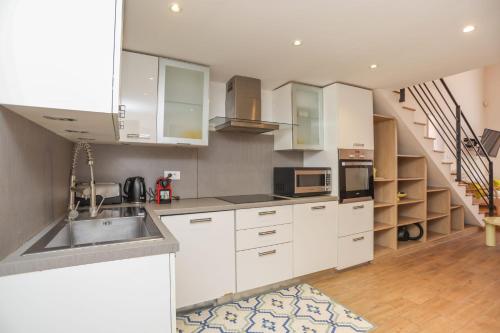 - une cuisine avec des placards blancs, un évier et un escalier dans l'établissement IMMOGROOM - Beautiful Duplex - 5 min from the beach - AC - SUQUET, à Cannes