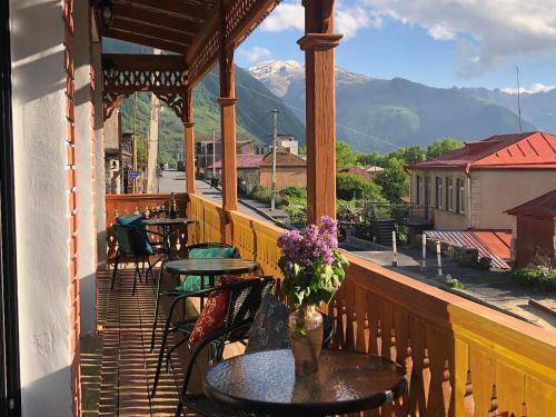 a balcony with tables and chairs and a view of mountains at Fiten house in Stepantsminda