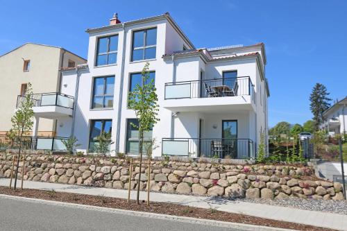 a white house with a stone retaining wall at Villa Anni - Ferienwohnung 04 mit Balkon in Göhren