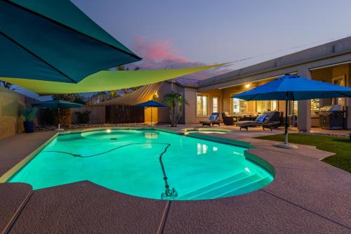 una piscina con sombrillas junto a una casa en Runaway Bay Chandler home, en Sun Lakes