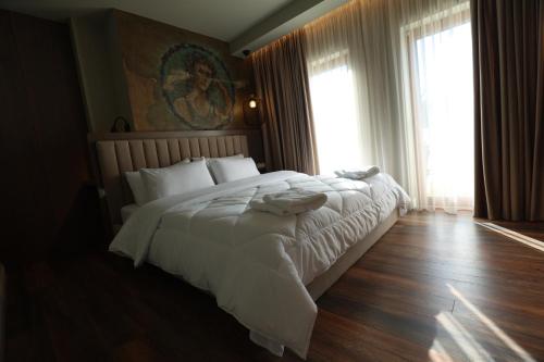a bedroom with a large bed with white sheets at Vila Borgjeze in Korçë