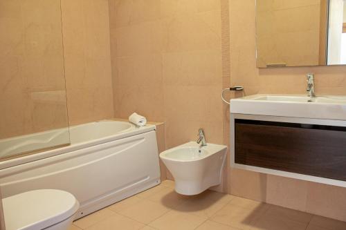 a bathroom with a sink and a toilet and a bath tub at Leta´s Beach House in Carvoeiro