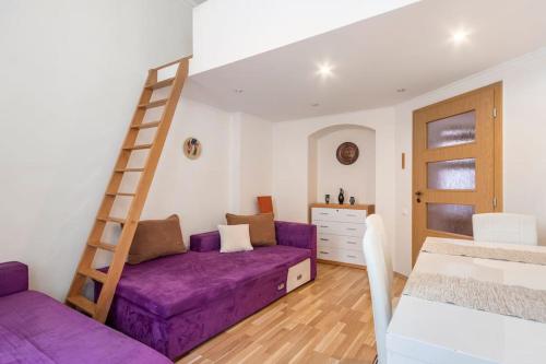 a living room with a purple couch and a ladder at Apartment on Masaryka 39 in Karlovy Vary