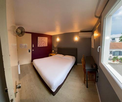 a small bedroom with a white bed and a window at Contact Hotel LE SUD Montpellier Aéroport Parc Expo Arena in Mauguio