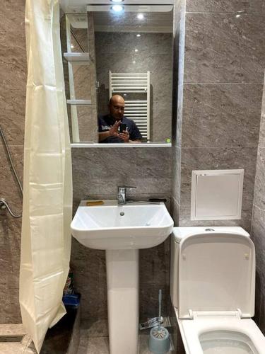 a man taking a picture of a bathroom with a toilet and sink at Aram Guest House in Sevan