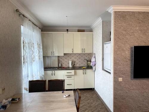 uma pequena cozinha com armários brancos e uma janela em Aram Guest House em Sevan