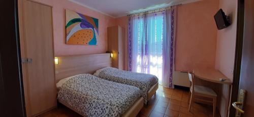 a bedroom with two beds and a window and a desk at Hotel Chiara in Sirmione