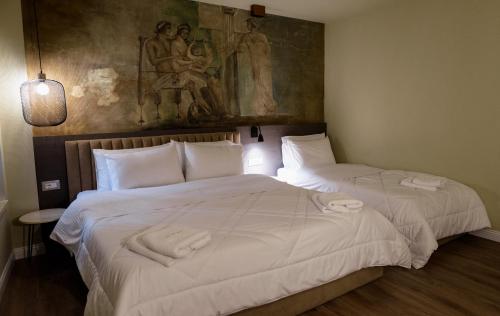 two beds in a room with a painting on the wall at Vila Borgjeze in Korçë