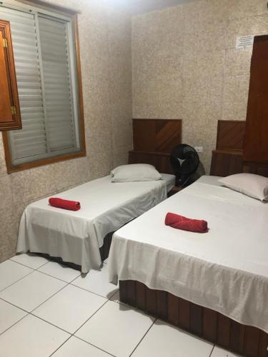 two beds in a room with red pillows on them at M-Blue Hotel in Jundiaí