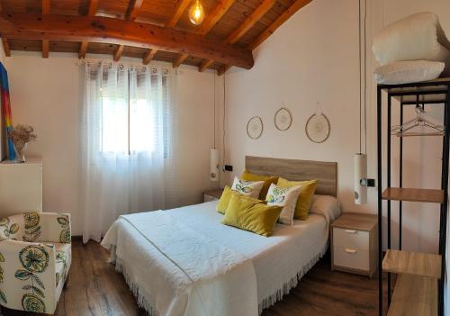 Un dormitorio con una cama con almohadas amarillas y una ventana en AlmadeMencía, en Pontevedra